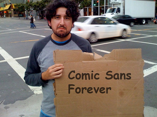 Man holding cardboard sign that says "comic sans forever"
